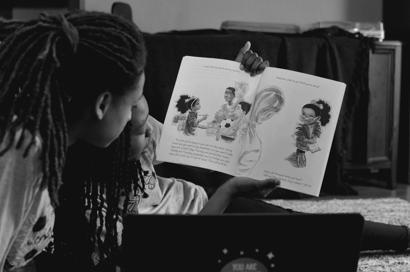 Two people reading a children's book together indoors.