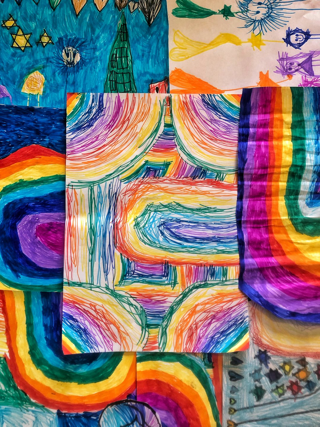 Children's drawings collage with rainbow arcs and stars.