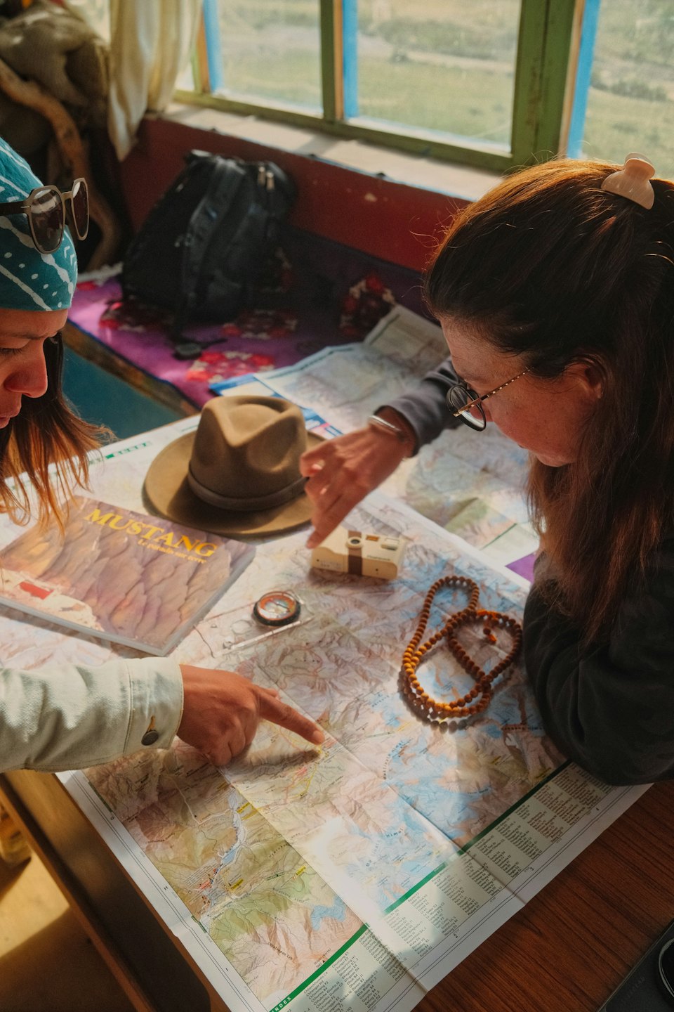 Two people examine a travel map on a wooden table.